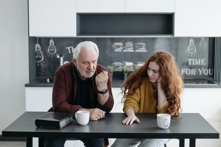 Two people talking across a kitchen table over coffee