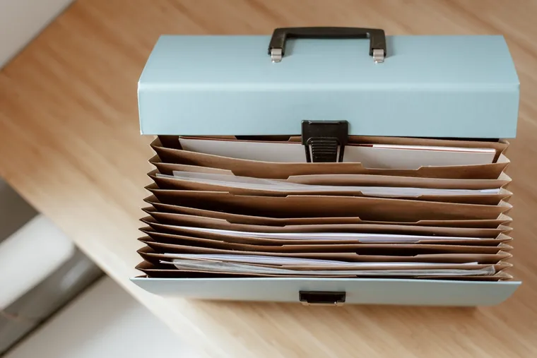An open document wallet of paperwork on a wooden table