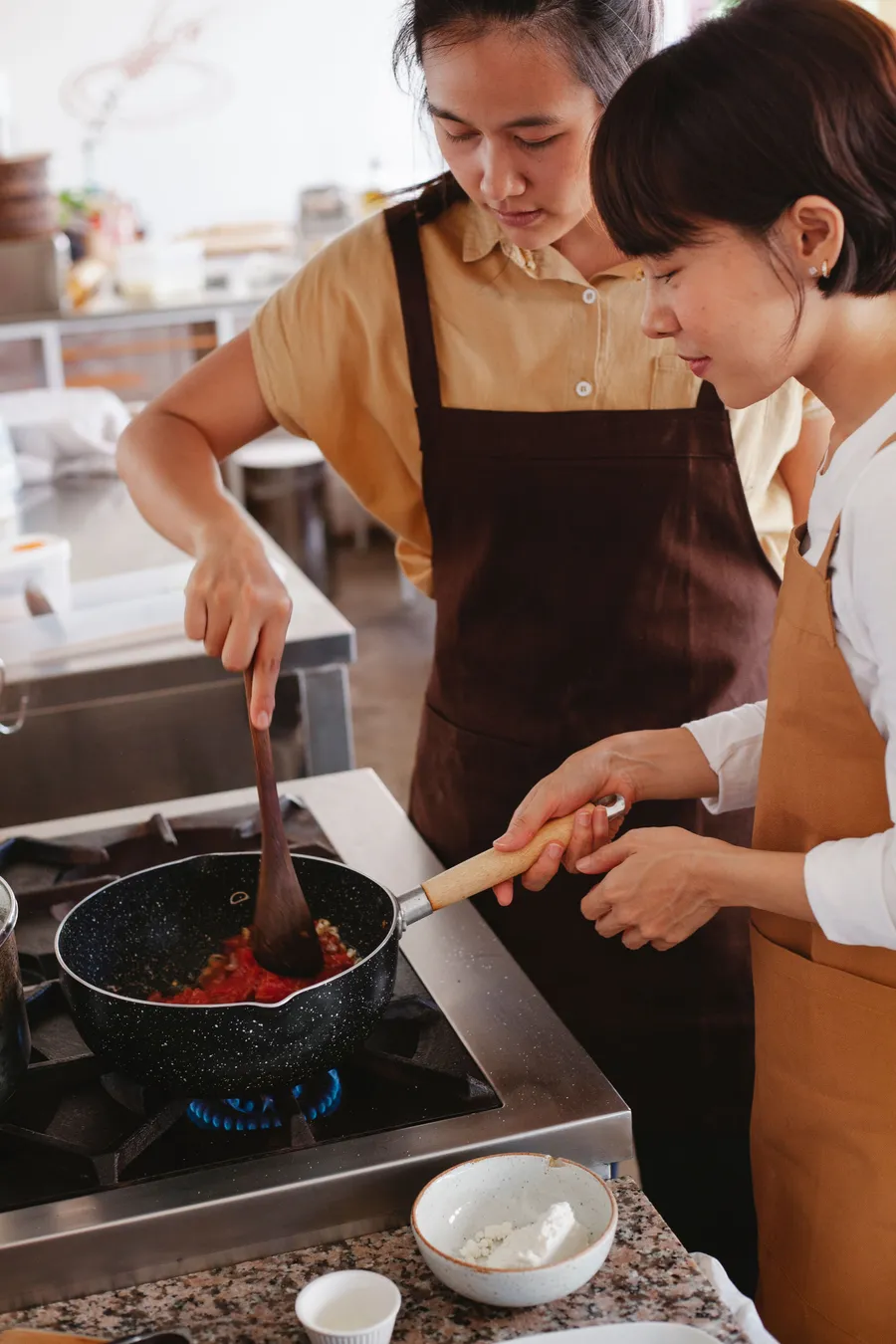 Two people cooking a meal together at a kitchen bench