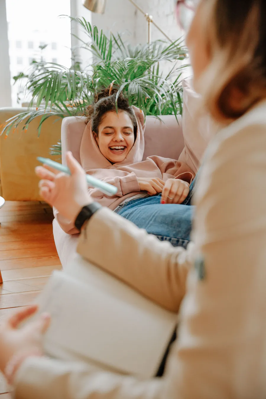 A young person laughing during a relaxed conversation indoors