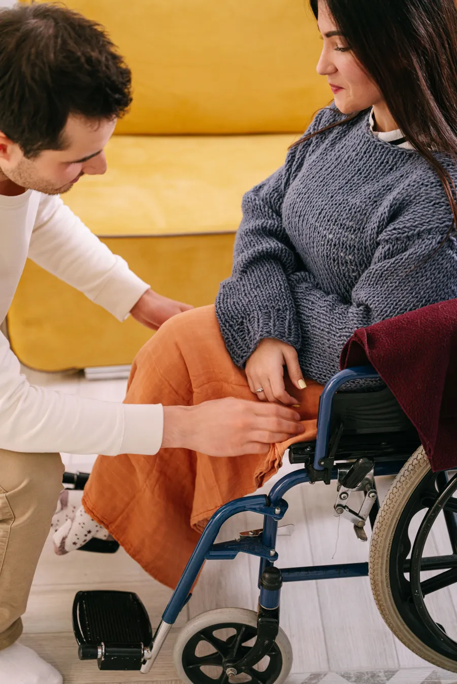 A support worker helping a woman who uses a wheelchair, indoors