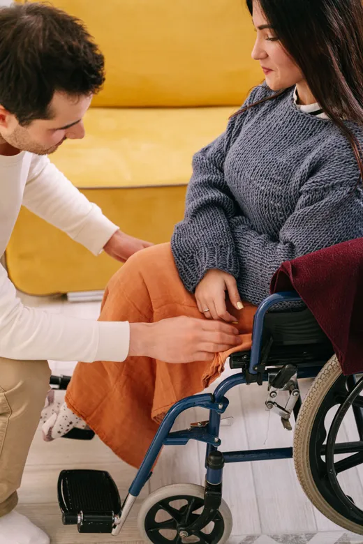 A support worker helping a woman who uses a wheelchair, indoors