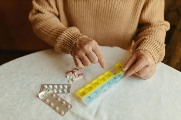 A person sorting daily tablets into a weekly organiser