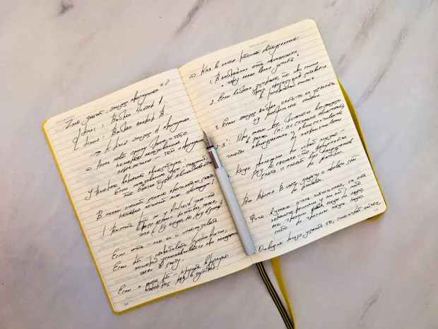 An open notebook of handwritten notes beside a pen