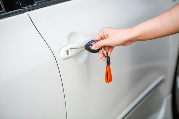 A hand unlocking a car door before a trip out